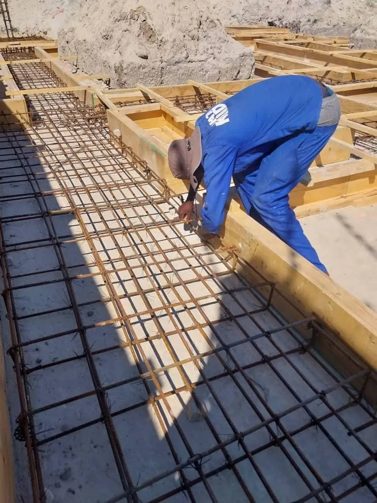 Team member tying reinforcement steel inside timber formwork
